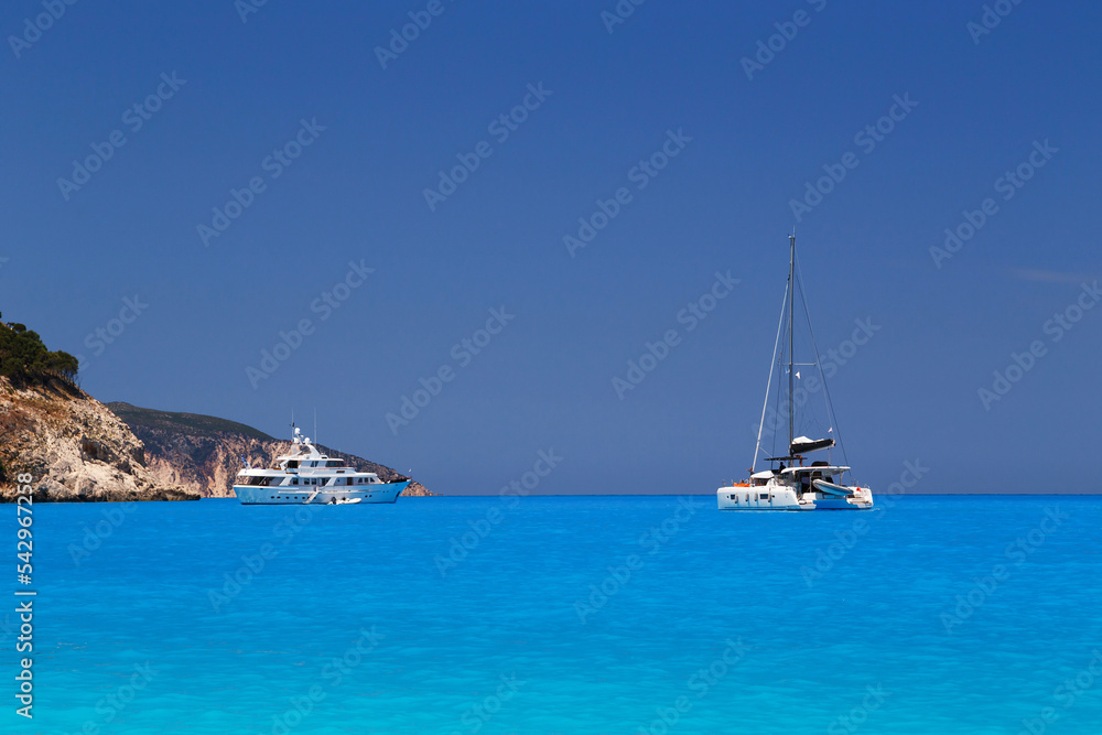 White yachts anchored in fantastic Myrtos Beach turquoise and blue bay. Summer scenery of famous and extremely popular travel destination in Cephalonia island, Greece, Europe. White yachts anchored in fantastic Myrtos Beach turquoise and blue bay. Summer scenery of famous and extremely popular travel destination in Cephalonia island, Greece, Europe.