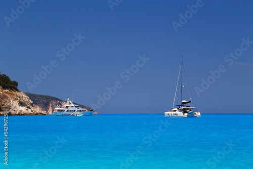 White yachts anchored in fantastic Myrtos Beach turquoise and blue bay. Summer scenery of famous and extremely popular travel destination in Cephalonia island, Greece, Europe.