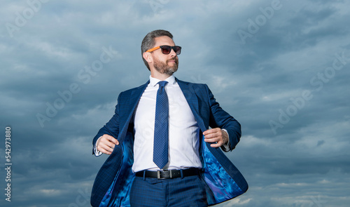 Guy wearing open suit jacket fluttering in wind sky background