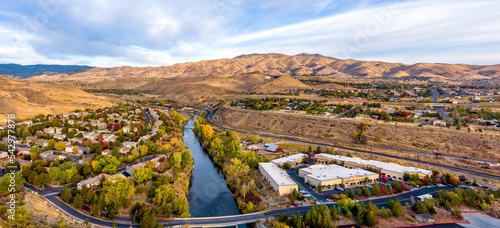 Aerial panoramic view of a beautiful Truckee River in Autumn with colorful trees, barren desert mountains, and a partly cloudy blue sky west of Reno Nevada. photo