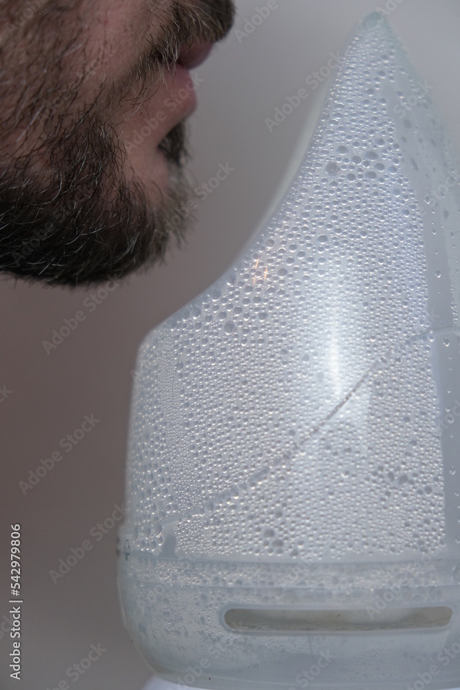 Inhalation and respiration. A man breathes steam to treat his