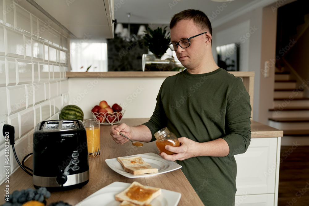 Adult caucasian man with down syndrome preparing breakfast