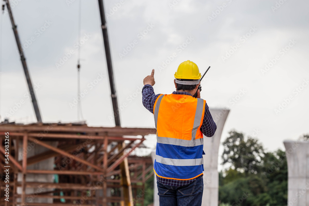 Rear view of Engineer under inspection and checking project at the building site, Foreman worker in hardhat at the infrastructure construction site Rear view of Engineer under inspection and checking project at the building site, Foreman worker in hardhat at the infrastructure construction site