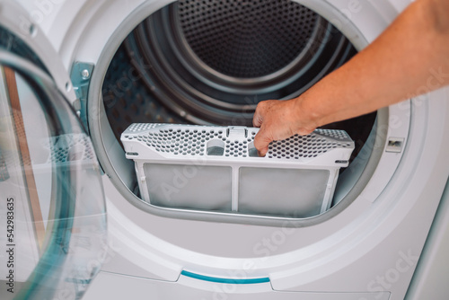 Housewife cleanup lints and dirt from tumble dryer filter. Clothes dryer lint filter that is covered with lint. Taking the lint out from dirty air filter of the dryer machine before use the machine.