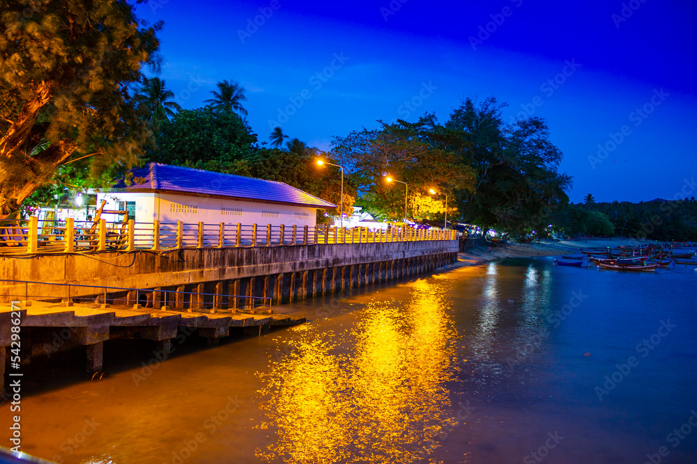 Fototapeta premium Pier at night with yellow lights on a background of blue sky