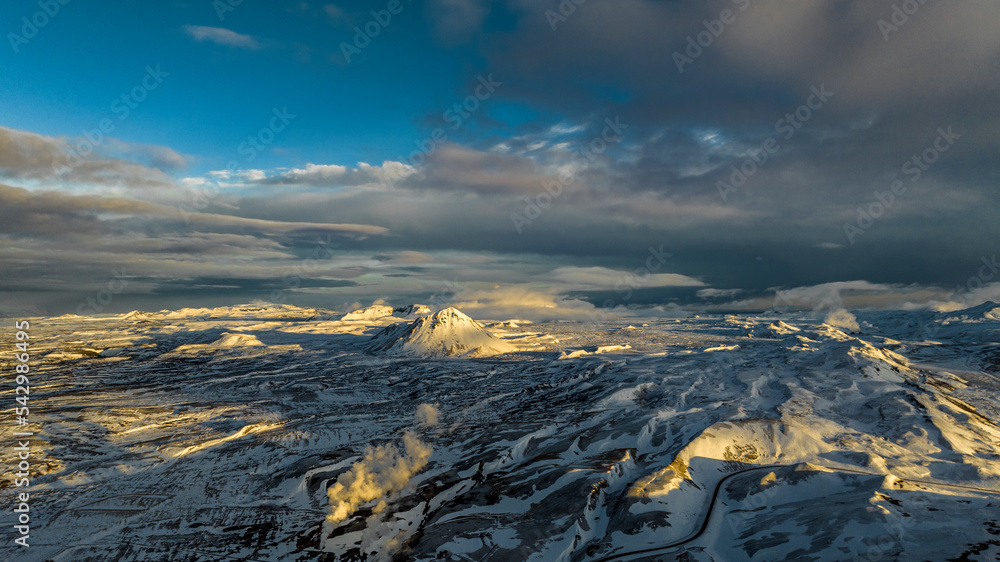 aerial view on morning winter beautiful mountains covered with snow in iceland with steam from geothermal plant