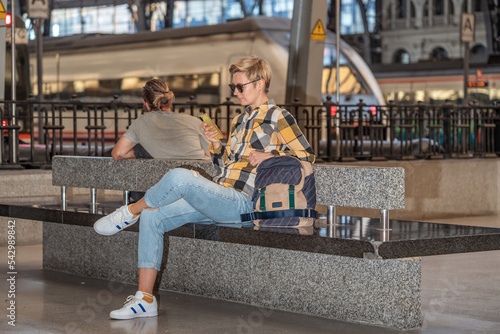 Adult 35s year old lesbian woman in plain shirt and jeans with backpack and sunglasses traveling by train in Europe. Train station in Barcelona, Spain. photo