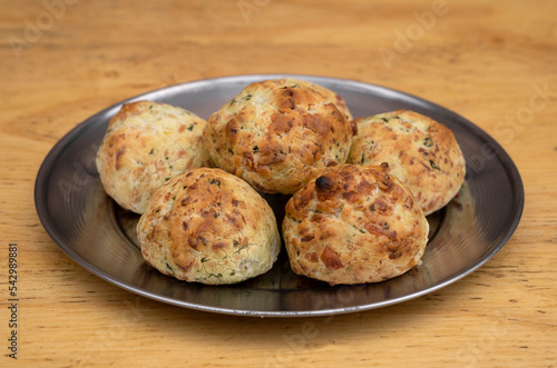 South American food. Closeup view of small, baked, cheese-flavored rolls, called chipa, in a metal dish on the wooden background. photo