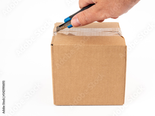 Cardboard box on a white background. Open the cardboard boxes with a utility knife. © Jakob