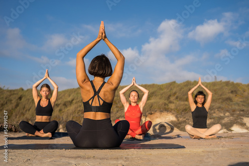 Back view of the tanned woman coach meditating with her students