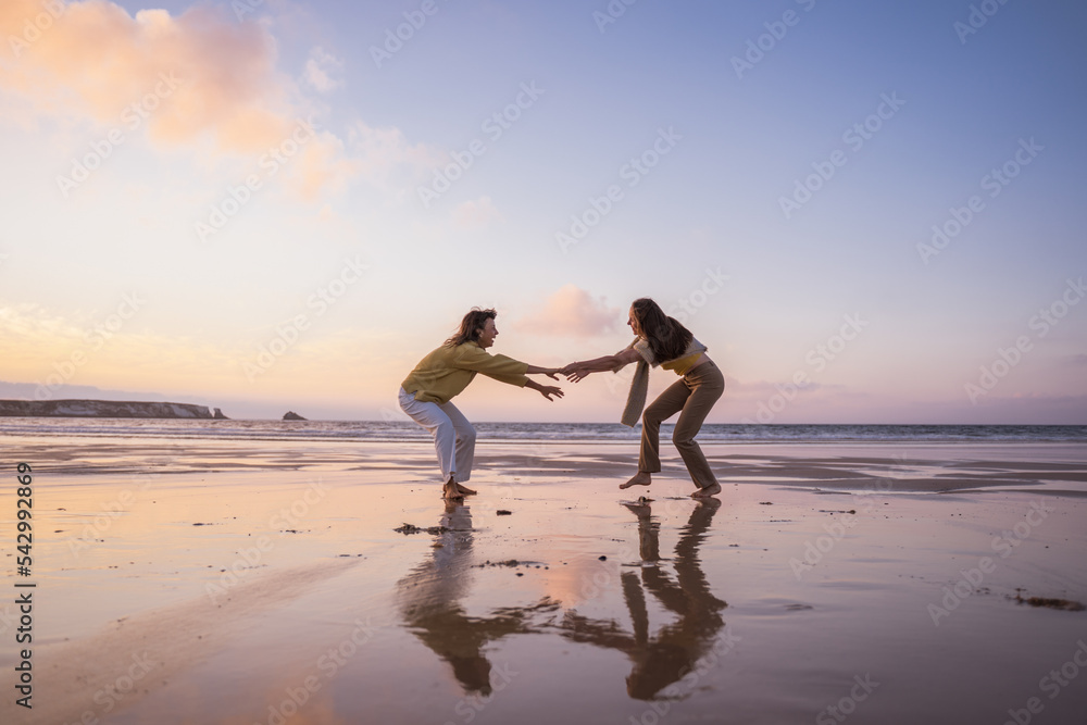 Two happy best friends holding hands and having fun at the sandy ocean beach Two happy best friends holding hands and having fun at the sandy ocean beach