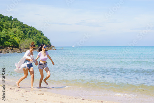 Happy female couple or bisexual couple enjoy walking along the beach together.