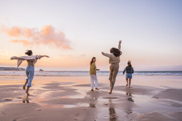 Happy friends having fun and running at the sunset