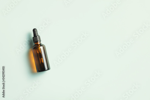 Amber glass dropper bottle with black lid on blue background. Skincare products   natural cosmetic. Beauty concept for face and body care. Banner