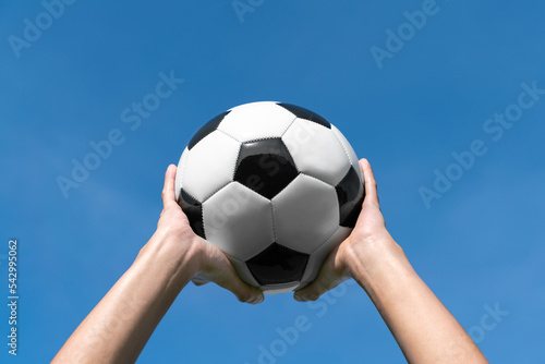 football player hold ball on hand for throw in soccer ball to team to kick or shoot to win goalkeaper then make a score in champion league with blue sky background © kunchainub