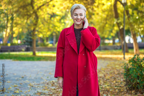 Portrait of a beautiful middle-aged woman in a red coat, autumn park