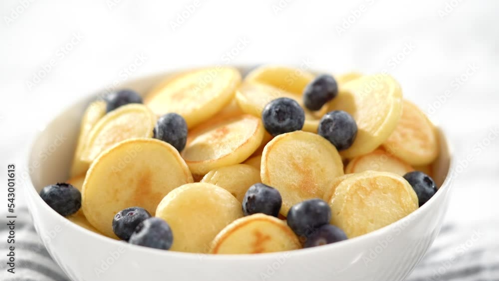Step by step. Freshly made mini pancake cereal with fresh blueberries in a white bowl. Step by step. Freshly made mini pancake cereal with fresh blueberries in a white bowl.