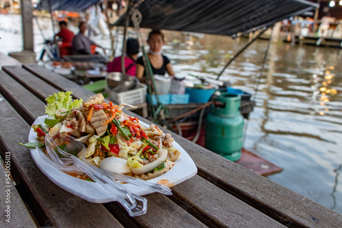 Canvas Print The spicy vietnamese sausage salad on dish with blurred kitchen on boat at background, Khlong Lat Mayom Floating Market, Thailand