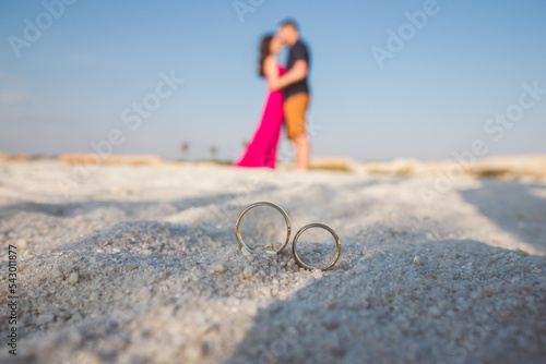 wedding ring on the beach with the bride and groom in the background