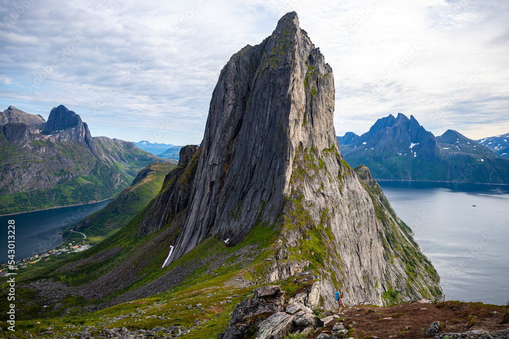 backpacker girl hiking on hesten overlooking Norway's famous segla mountain, senja island; hesten trail head, Norway's famous fjords with mighty mountains above the sea backpacker girl hiking on hesten overlooking Norway's famous segla mountain, senja island; hesten trail head, Norway's famous fjords with mighty mountains above the sea