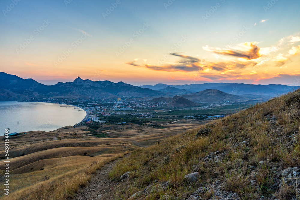 Beautiful landscape with sea bay, mountains and coastal village in mountainous area. Picturesque view with hills and township at sea coast on evening after sunset. Koktebel near Karadag, Crimea