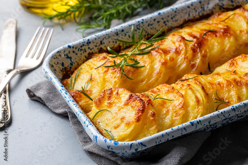 Potato gratin - graten (baked potatoes with cream and cheese) with rosemary and forks (Turkish name; Kremali patates)