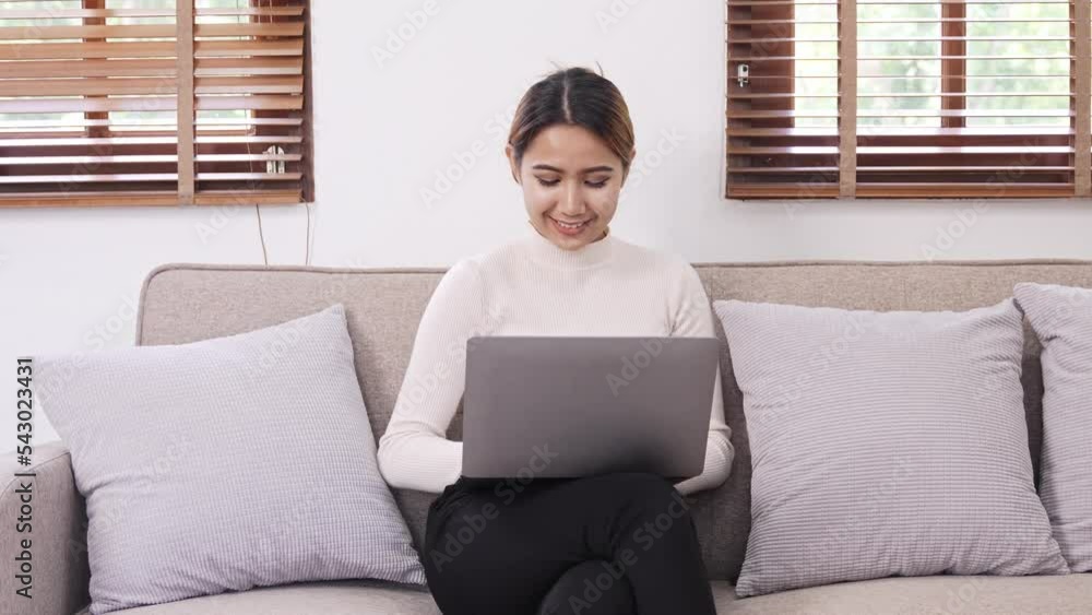 Asian woman using laptop working on sofa at home. students studying online at home