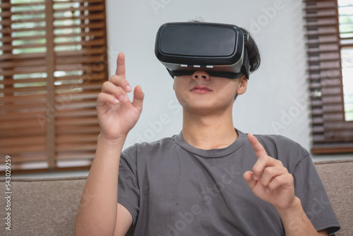 relieve stress on vacation Happy Asian white man relaxing at home playing VR 3D virtual reality game on vacation.