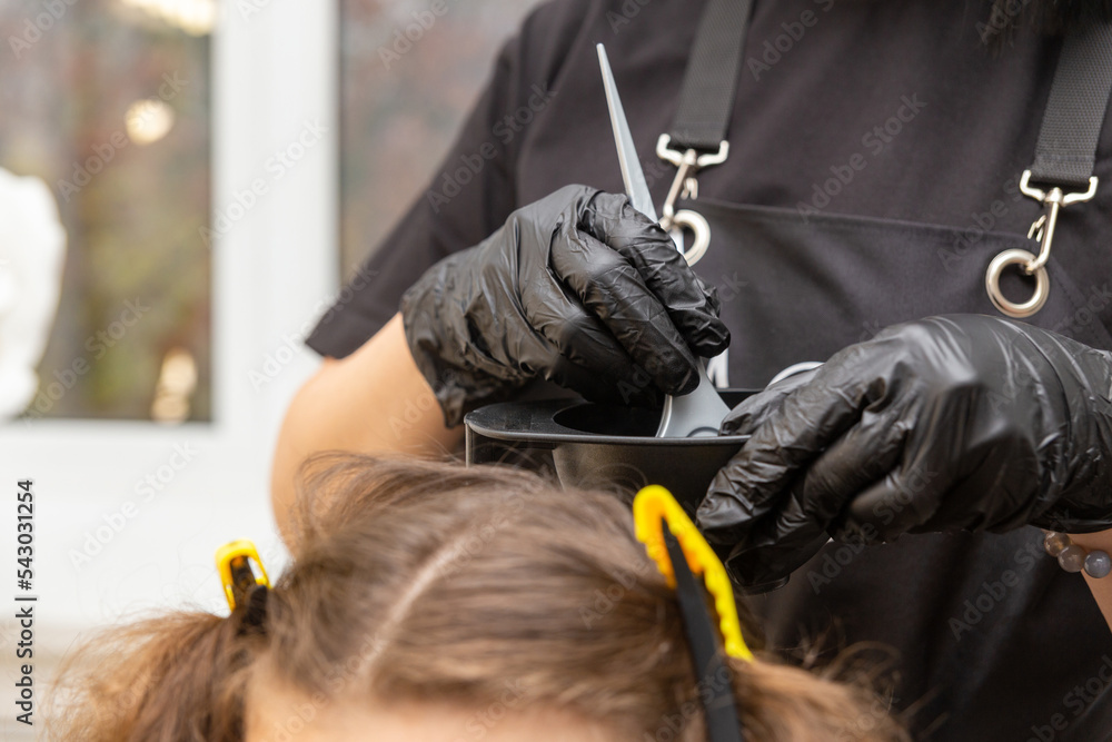 Girl in black rubber protective gloves holding a brush in her hands