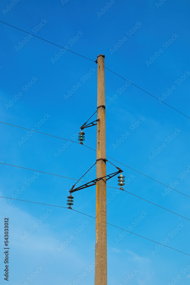 Concrete pillar with electric cables against the blue sky. High voltage electric power line closeup Concrete pillar with electric cables against the blue sky. High voltage electric power line closeup
