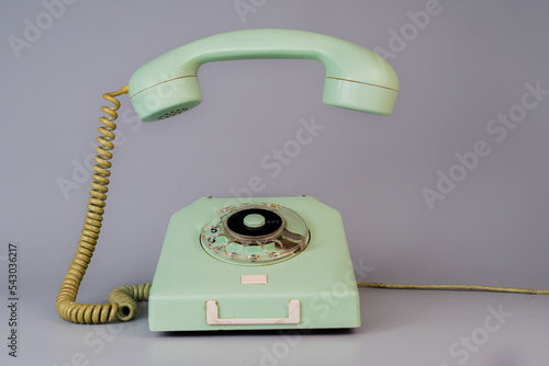 Photos Old blue aged rotary telephone with removed hanging receiver on grey background