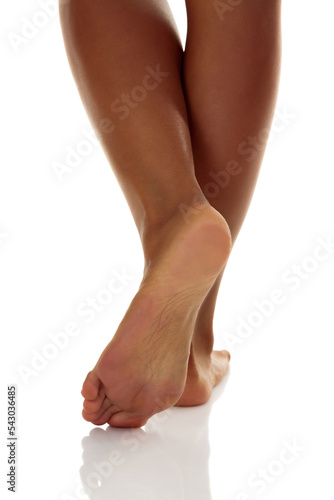 Closeup shot of tanned female feet, isolated on white background