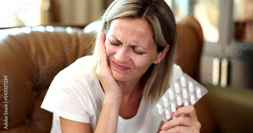 Portrait of woman hurting tooth and taking painkillers pill