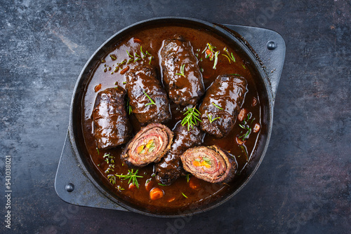 Traditional slow cooked German wagyu beef roulades with vegetable and bacon served in spicy gravy sauce as top view in a design pot with copy space photo