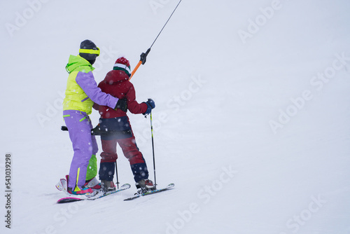 A woman and a child are towed uphill on a t-bar in a snowfall. Copy space. Selective focus. photo