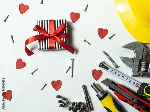 Construction tools and gift on white background with small red hearts and copy space. Construction greeting card for Valentines day. Repair home with love. Gifts for lover. Buying presents for man. photo