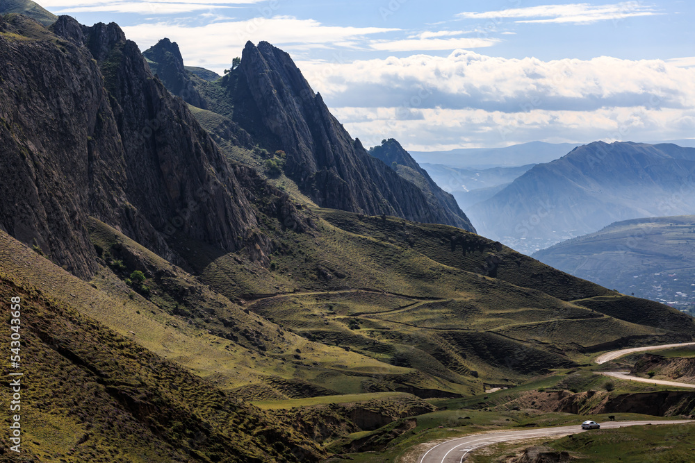 A long winding mountain road, against the backdrop of high relief, sharp mountains. A long winding mountain road, against the backdrop of high relief, sharp mountains.