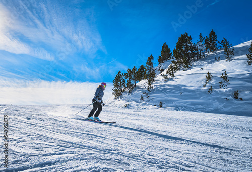 Woman skiing down the ski slope or piste in Pyrenees Mountains. Winter ski holidays in El Tarter, Grandvalira, Andorra