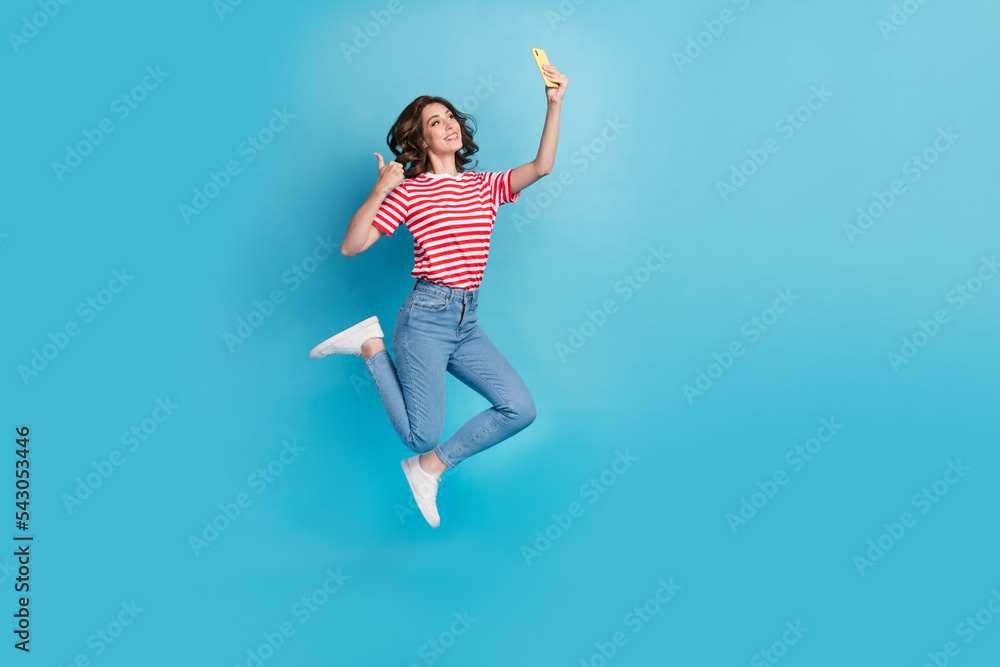 Full length photo of excited cute lady wear striped t-shirt recording video vlog modern gadget thumb up isolated blue color background