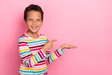 Portrait of positive nice boy with wavy hairdo dressed striped long sleeve indicating empty space isolated on pink color background