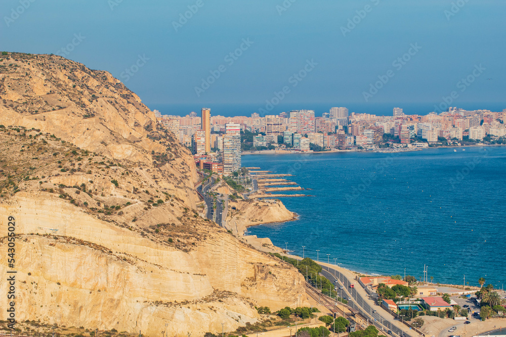 Panorámica del paisaje marítimo de la ciudad de Alicante con su playa bajo un cielo azul con algunas nubes y el tranquilo mar en el último viaje de trabajo. 