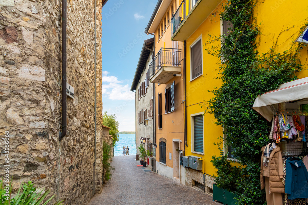 A narrow alley of shops and cafes leading to the lakefront promenade at the town of Sirmione, Italy, on the shores of Lake Garda.