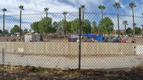 Moving view of homeless tents and palm trees along flood control channel near Chatsworth Station in the San Fernando Valley.  