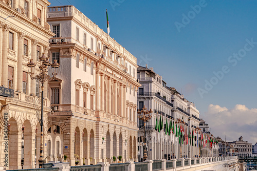 Algiers, Zighout Youcef Boulevard, Council of the Nation, Bank of Algeria and Casbah municipality white buildings with Arab league flag poles, electric street post lights and chamber of commerce photo