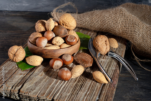 wooden bowl with various nuts and a nutcracker on a wooden board.