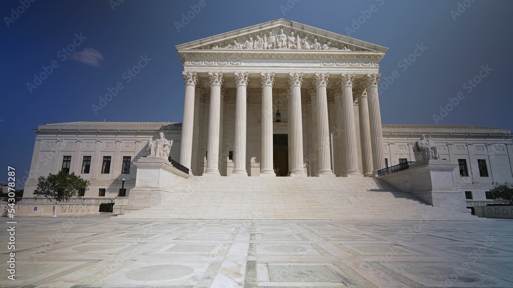 Wide angle view of facade of US Supreme Court building with Authority of Justice sculpture in front in Washington, DC on a sunny summer day.