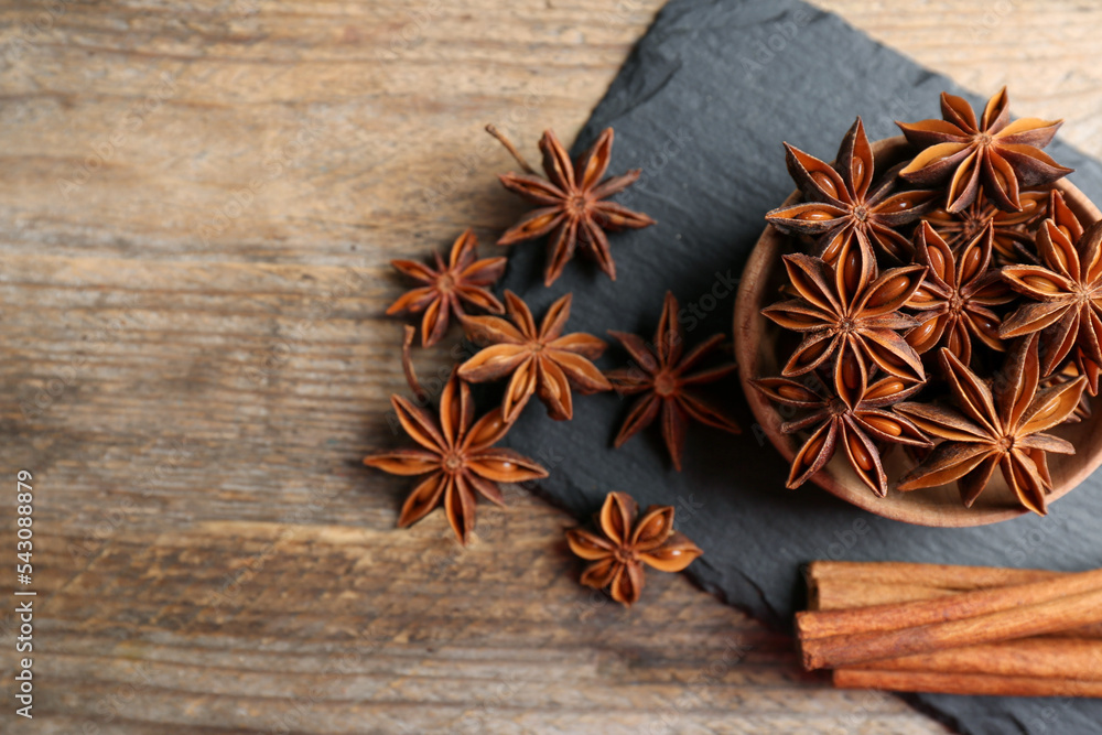 Aromatic cinnamon sticks and anise stars on wooden table, flat lay. Space for text