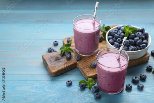 Glasses of blueberry smoothie with mint and fresh berries on turquoise wooden table. Space for text