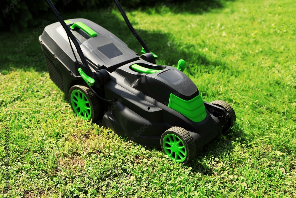 Cutting green grass with lawn mower in garden Cutting green grass with lawn mower in garden