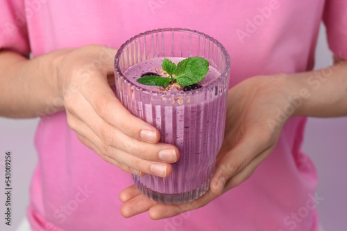 Woman with glass of delicious blackberry smoothie on white background, closeup